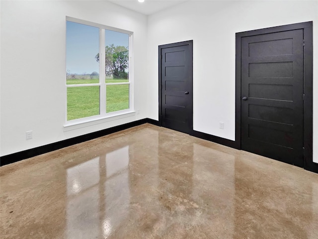 spare room with concrete flooring and baseboards