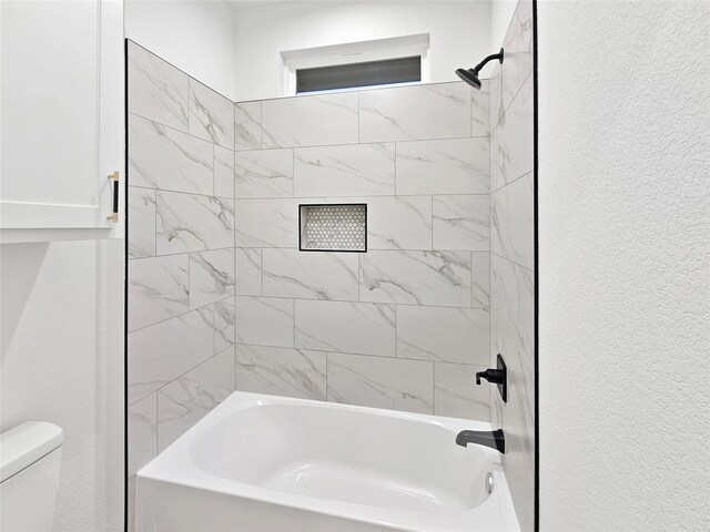 full bathroom featuring toilet, a textured wall, and washtub / shower combination