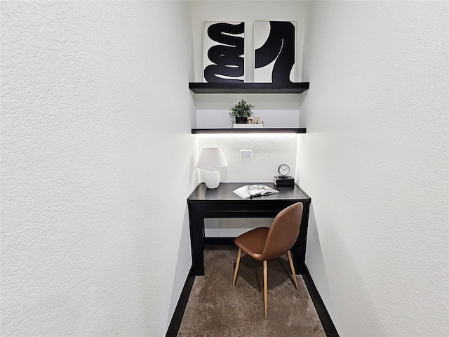 office with a textured wall, concrete floors, and baseboards