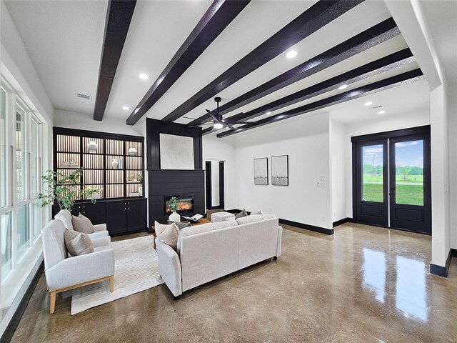 living area with beamed ceiling, baseboards, and concrete flooring