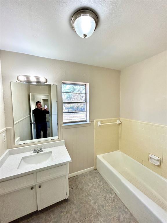 140 Vz County Road 2153, Canton, TX 75103 - bathroom featuring a garden tub, vanity, a textured ceiling, a wainscoted wall, and tile patterned floors