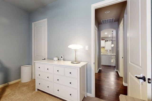 corridor featuring arched walkways, carpet flooring, visible vents, and baseboards