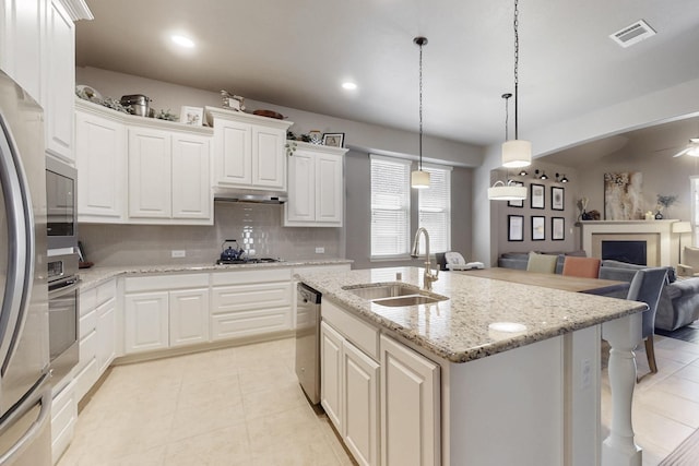 kitchen with visible vents, under cabinet range hood, a sink, stainless steel appliances, and open floor plan