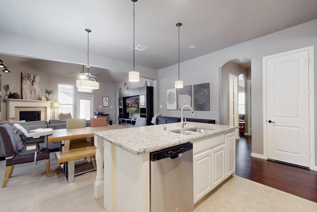 kitchen featuring arched walkways, dishwasher, a sink, a kitchen island with sink, and open floor plan