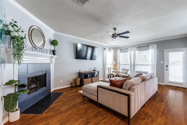 living area with a textured ceiling, hardwood / wood-style flooring, ceiling fan, ornamental molding, and visible vents