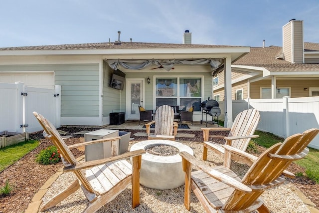 rear view of property featuring fence, a ceiling fan, a patio, and an outdoor fire pit