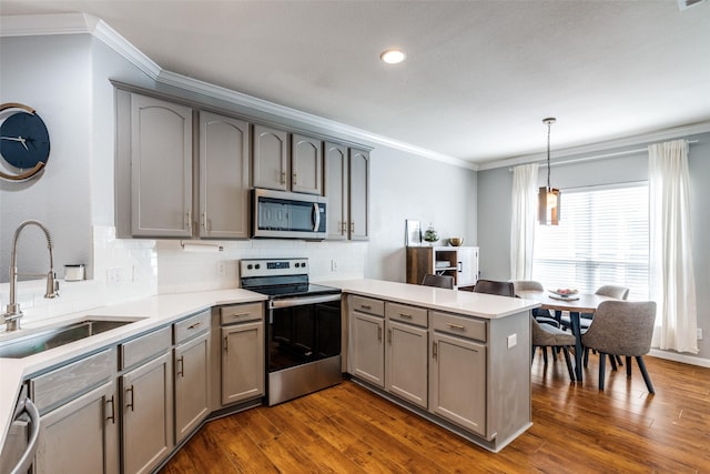 kitchen featuring a peninsula, ornamental molding, stainless steel appliances, and a sink