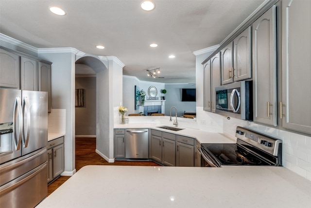 kitchen featuring appliances with stainless steel finishes, gray cabinets, ornamental molding, and a sink
