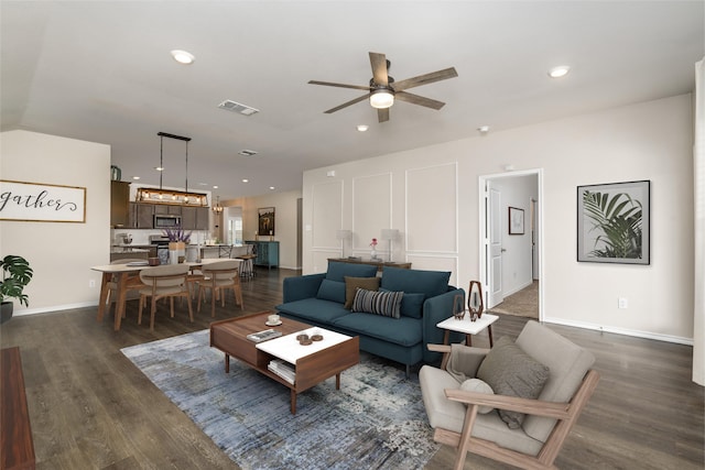 living room with dark wood-type flooring, visible vents, baseboards, and a ceiling fan