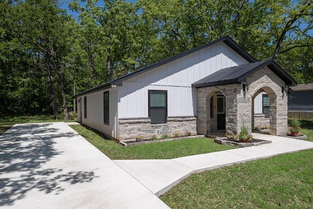 view of front of property featuring metal roof, a front yard, and stone siding
