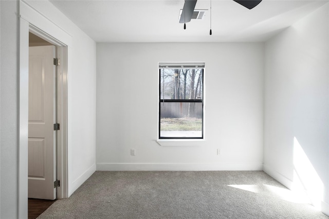 empty room featuring visible vents, ceiling fan, dark colored carpet, and baseboards
