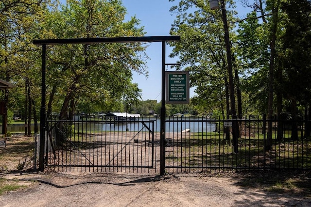 view of gate with fence and a water view