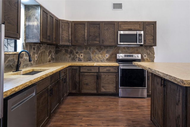 kitchen with visible vents, a sink, dark brown cabinetry, stainless steel appliances, and decorative backsplash