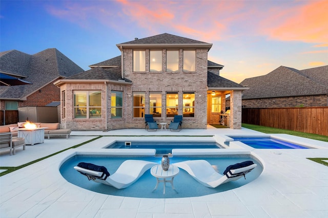 5841 Willow Ln, The Colony, TX 75056 - rear view of house featuring a fire pit, brick siding, and a pool with connected hot tub