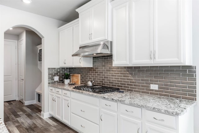 5841 Willow Ln, The Colony, TX 75056 - kitchen with stainless steel gas cooktop, under cabinet range hood, arched walkways, dark wood-style floors, and white cabinets
