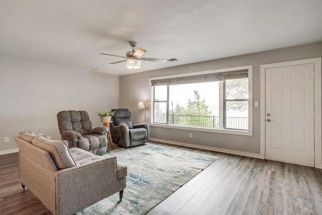 living room with baseboards, a ceiling fan, wood finished floors, and visible vents