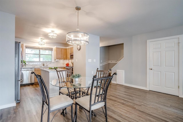 dining space with baseboards, wood finished floors, and a notable chandelier