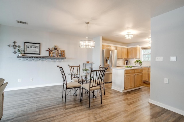 dining space with light wood finished floors, baseboards, visible vents, and a notable chandelier