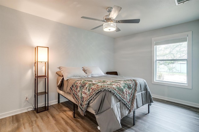 bedroom with wood finished floors, baseboards, and ceiling fan