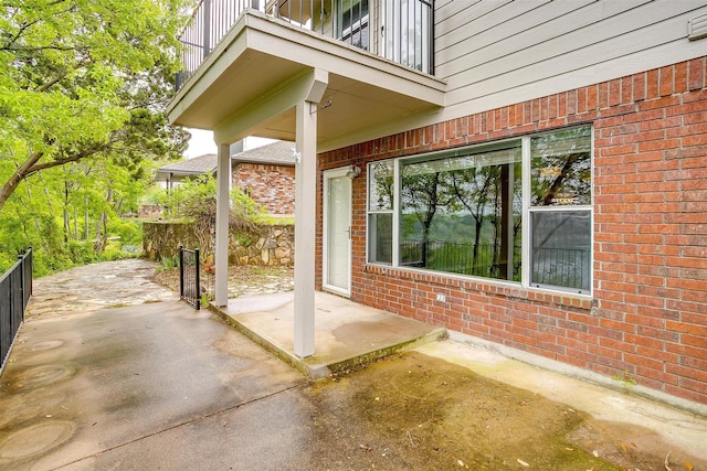 view of patio featuring fence and a balcony
