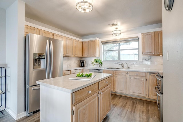 kitchen featuring visible vents, light brown cabinets, stainless steel appliances, and a sink