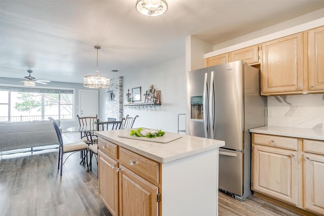 kitchen with light brown cabinetry, stainless steel fridge with ice dispenser, light countertops, a center island, and light wood-style flooring