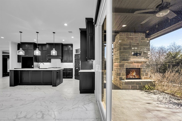 1661 Ethan Cir, Midlothian, TX 76065 - kitchen featuring a ceiling fan, an outdoor stone fireplace, a sink, decorative backsplash, and light countertops