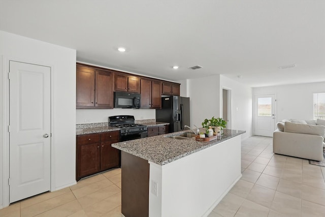 6436 Auburn Dale Rd, Pilot Point, TX 76258 - kitchen with black appliances, a sink, light stone counters, light tile patterned floors, and a center island with sink