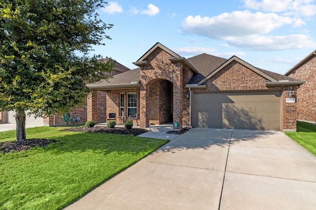 view of front of home with driveway, a front yard, roof with shingles, brick siding, and a garage