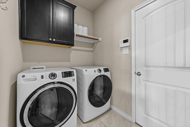 laundry room with washer and clothes dryer, cabinet space, baseboards, and light tile patterned floors