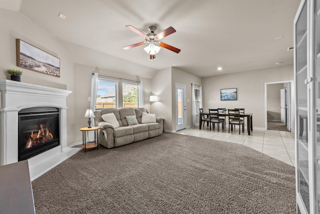 living room with light tile patterned floors, baseboards, ceiling fan, light carpet, and a glass covered fireplace