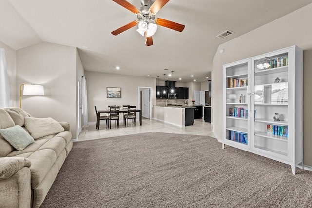 living area featuring light colored carpet, visible vents, light tile patterned floors, and a ceiling fan