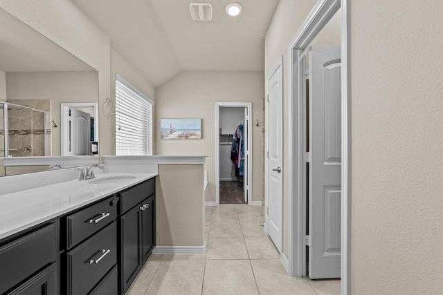 bathroom featuring vanity, a walk in closet, vaulted ceiling, a shower stall, and tile patterned floors