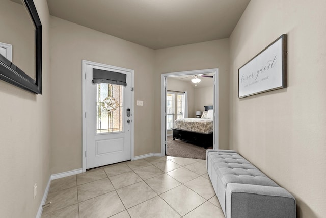 foyer featuring light tile patterned floors, baseboards, and ceiling fan