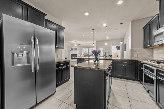 kitchen with light tile patterned floors, a peninsula, stainless steel appliances, and dark cabinetry