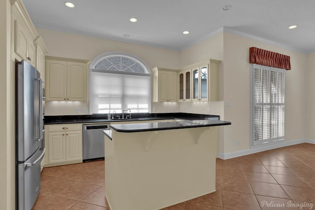 kitchen with light tile patterned flooring, appliances with stainless steel finishes, glass insert cabinets, dark countertops, and ornamental molding