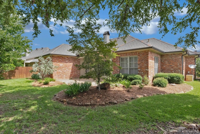 exterior space with a front lawn, a chimney, fence, and brick siding