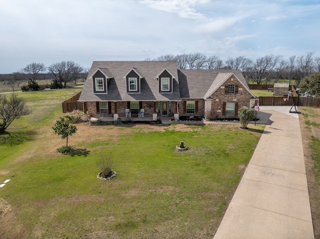 view of front facade featuring concrete driveway, roof with shingles, a front lawn, covered porch, and brick siding