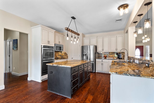 kitchen with stainless steel appliances, dark wood finished floors, a sink, visible vents, and light stone countertops