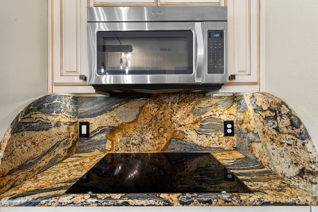 room details with stainless steel microwave, backsplash, and black electric stovetop
