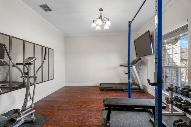 workout room featuring crown molding, wood finished floors, baseboards, visible vents, and an inviting chandelier