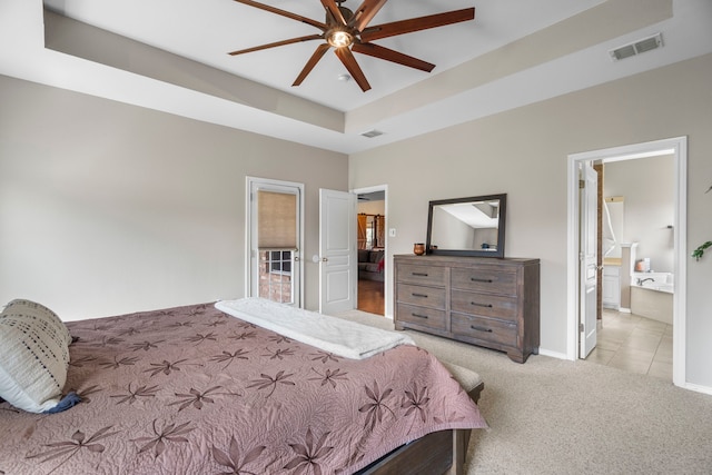 bedroom with baseboards, a tray ceiling, visible vents, and light colored carpet