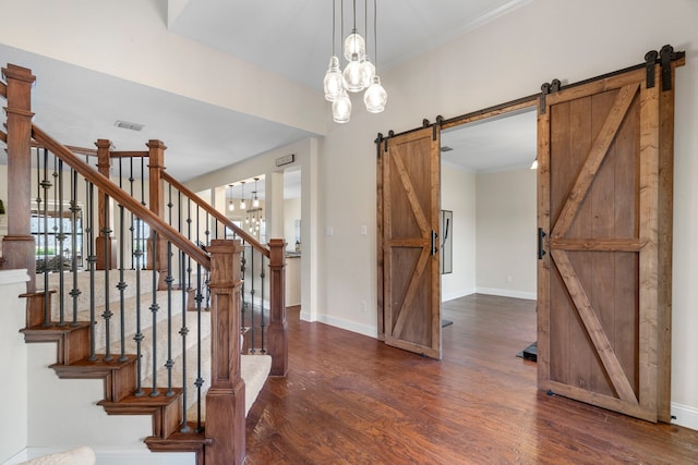 staircase featuring a wealth of natural light, crown molding, a barn door, and wood finished floors
