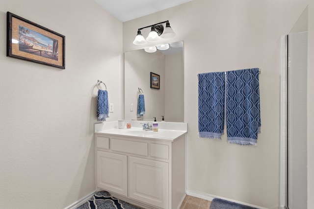 bathroom with baseboards, a shower with shower door, and vanity
