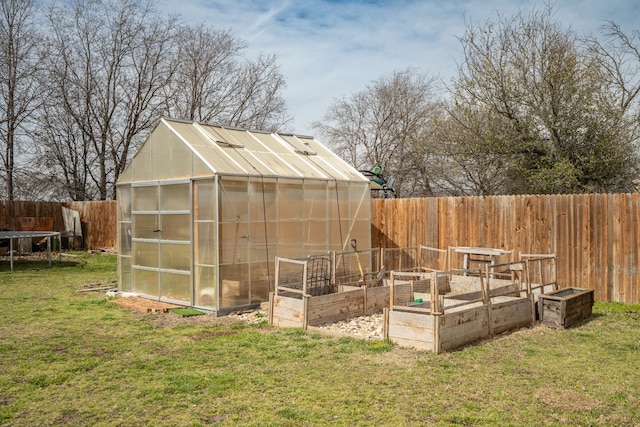 view of greenhouse featuring a fenced backyard, a vegetable garden, and a lawn