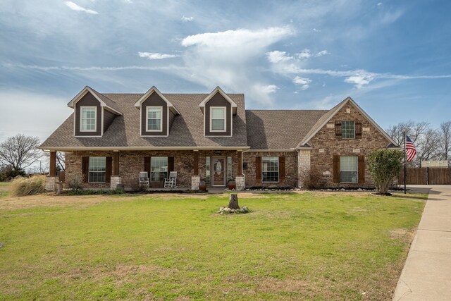 new england style home featuring brick siding, a shingled roof, and a front lawn