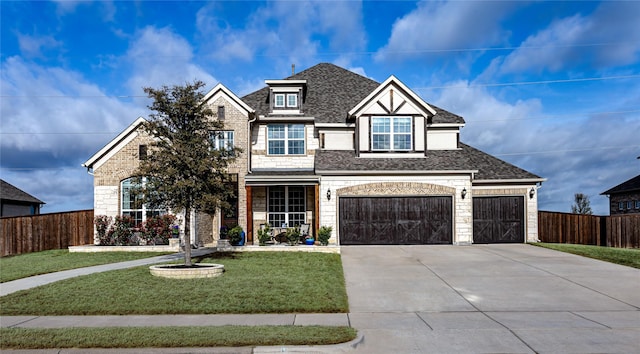view of front of property with fence, a front lawn, concrete driveway, a shingled roof, and stone siding