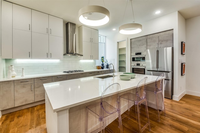 426 W 9th St Unit 105, Dallas, TX 75208 - kitchen featuring wall chimney range hood, decorative backsplash, a kitchen bar, appliances with stainless steel finishes, and a sink