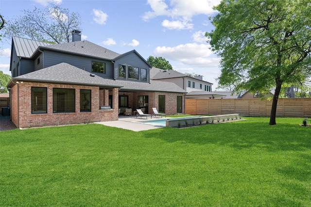 back of house featuring brick siding, a fenced backyard, a patio area, and a lawn