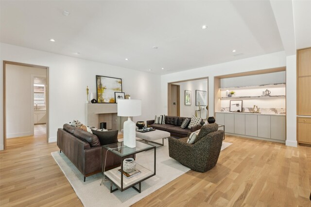 living area with recessed lighting, light wood finished floors, baseboards, and a fireplace